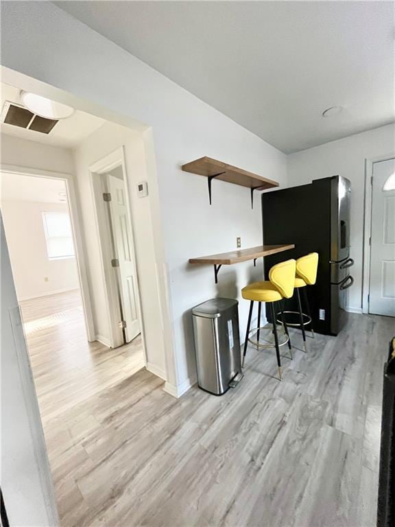 interior space with light hardwood / wood-style flooring, fridge, and a breakfast bar area