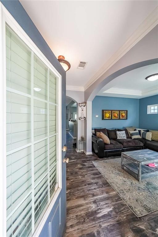 7835 Keepsake Ln, Flowery Branch, GA 30542 - living room featuring arched walkways, dark wood-type flooring, crown molding, and baseboards