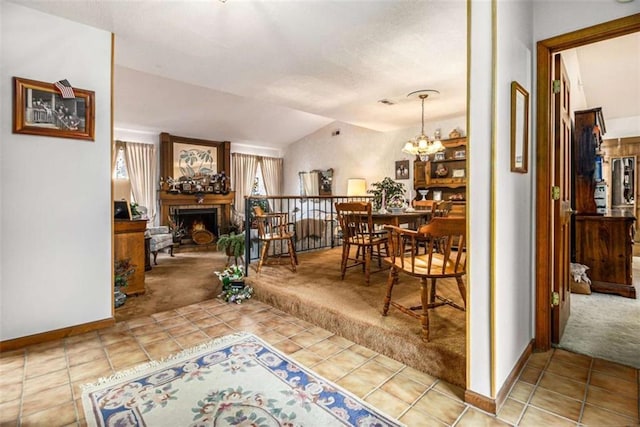 hall featuring lofted ceiling, light carpet, and an inviting chandelier