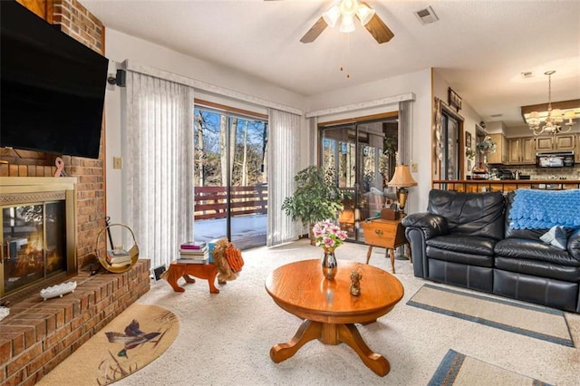 living room with a brick fireplace and ceiling fan with notable chandelier