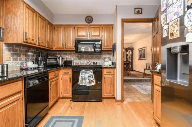 kitchen featuring light hardwood / wood-style flooring, dark stone countertops, decorative backsplash, and black appliances