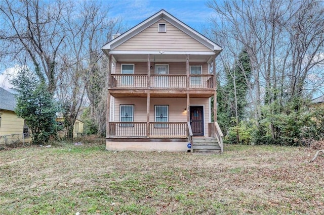 view of front facade with a balcony, a porch, and a front yard