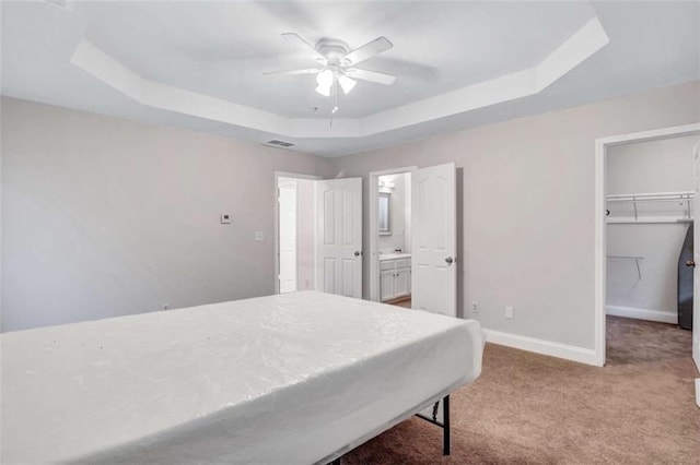 bedroom featuring a raised ceiling, ceiling fan, light carpet, and a closet