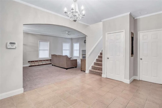 carpeted entrance foyer featuring crown molding and ceiling fan with notable chandelier