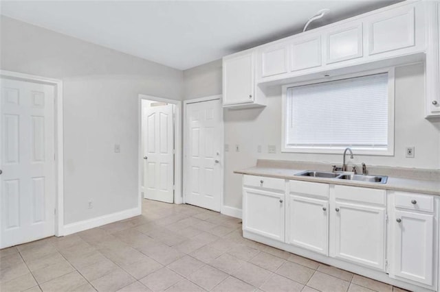 kitchen with light tile patterned floors, white cabinetry, and sink