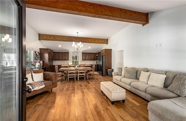 living room featuring light hardwood / wood-style floors, beamed ceiling, and a notable chandelier