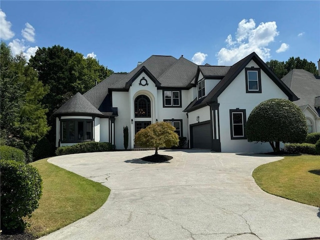 view of front of home featuring a garage, concrete driveway, a front lawn, and stucco siding