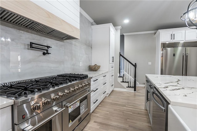 kitchen featuring crown molding, tasteful backsplash, white cabinetry, high quality appliances, and premium range hood