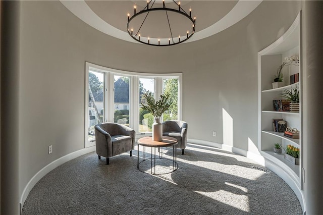 living area with built in features, baseboards, a notable chandelier, and carpet flooring