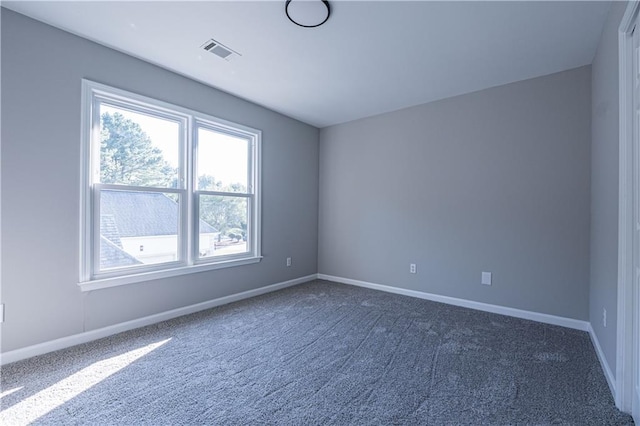 unfurnished room featuring dark colored carpet, visible vents, and baseboards