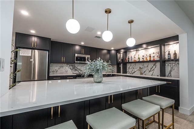 kitchen with stainless steel appliances, pendant lighting, and backsplash