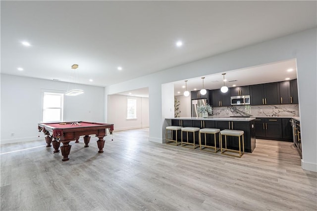 game room featuring baseboards, a healthy amount of sunlight, and light wood-style floors