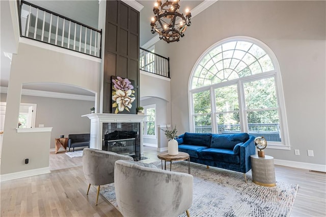 living room with light wood-style flooring, a high end fireplace, and crown molding