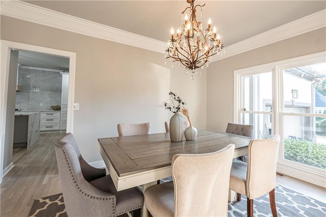 dining space with a chandelier, crown molding, baseboards, and wood finished floors