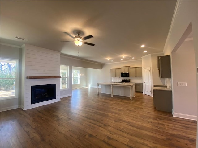 unfurnished living room with ornamental molding, a healthy amount of sunlight, dark wood-type flooring, and ceiling fan