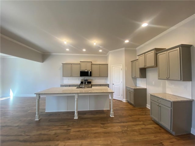 kitchen with sink, gray cabinetry, dark hardwood / wood-style flooring, light stone counters, and a center island with sink