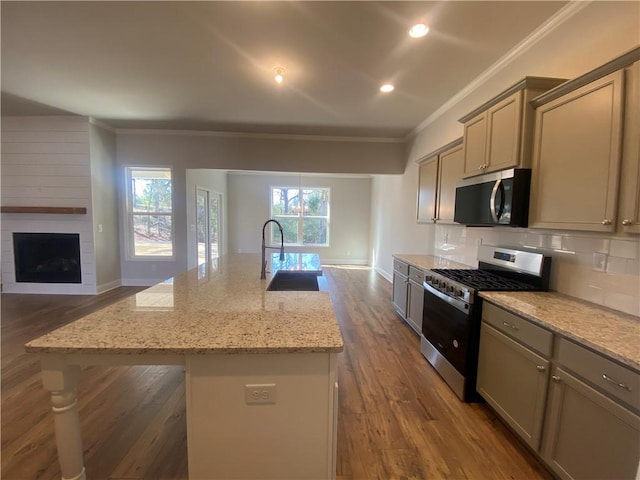 kitchen with crown molding, appliances with stainless steel finishes, sink, and an island with sink