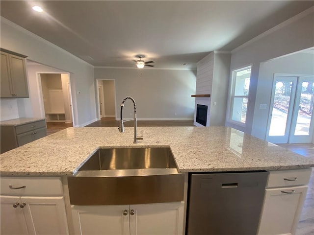 kitchen with sink, a fireplace, light stone countertops, and black dishwasher