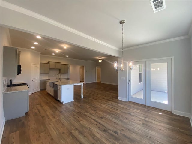 kitchen with dark wood-type flooring, an inviting chandelier, decorative light fixtures, and a kitchen island with sink