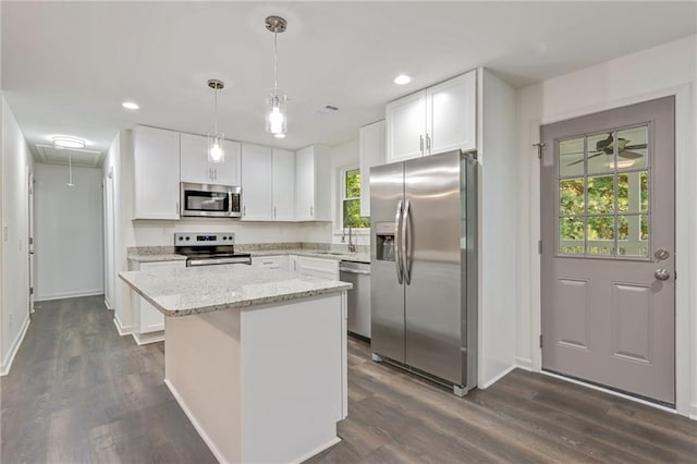 kitchen featuring white cabinets, decorative light fixtures, stainless steel appliances, and a kitchen island