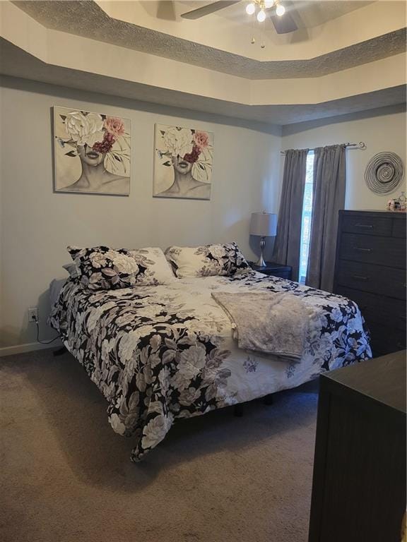 bedroom with ceiling fan, carpet flooring, and a raised ceiling