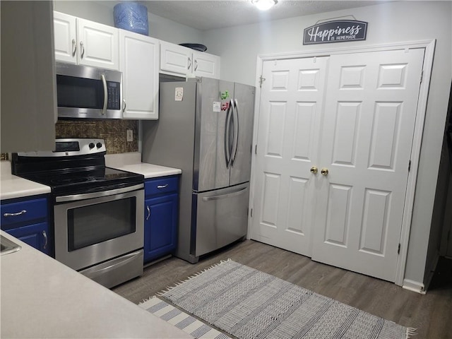 kitchen featuring blue cabinets, dark wood-type flooring, white cabinets, and appliances with stainless steel finishes