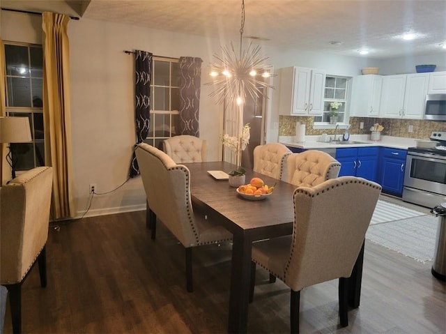 dining area with wood-type flooring, sink, and a notable chandelier