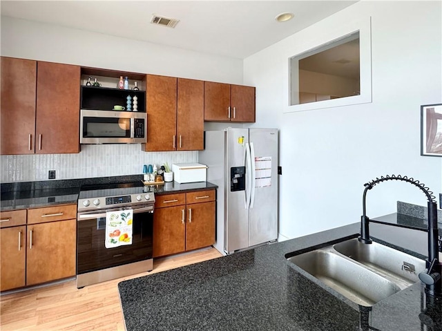 kitchen with visible vents, a sink, open shelves, stainless steel appliances, and decorative backsplash