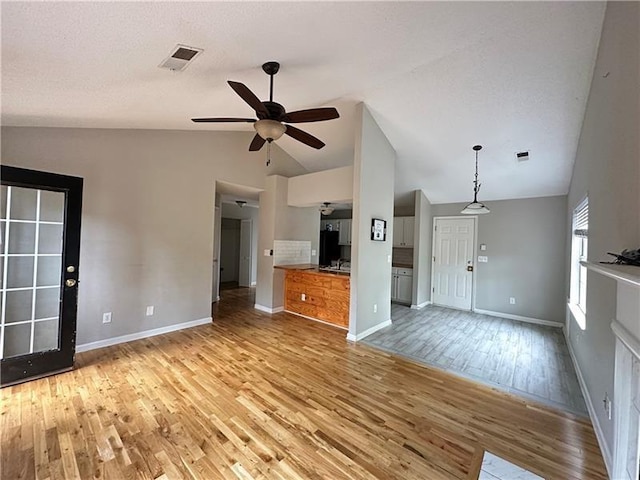 unfurnished living room featuring ceiling fan, vaulted ceiling, and light hardwood / wood-style floors