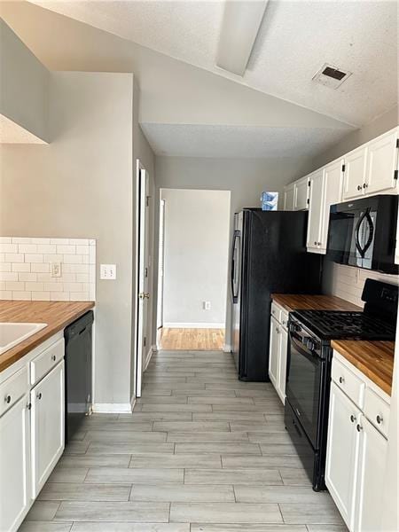 kitchen with butcher block counters, white cabinetry, tasteful backsplash, and black appliances