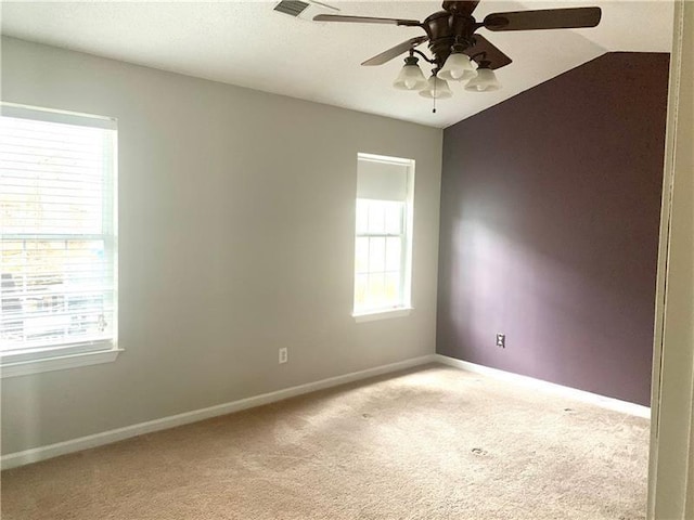 carpeted spare room featuring ceiling fan, vaulted ceiling, and a wealth of natural light