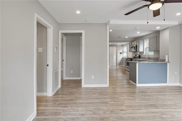 kitchen with gray cabinetry, light stone countertops, sink, light hardwood / wood-style floors, and stainless steel appliances