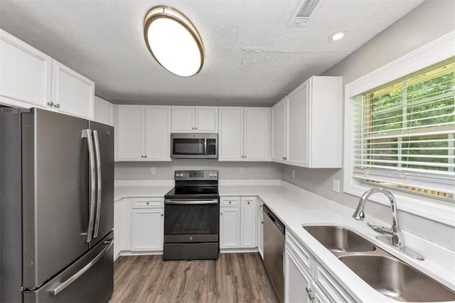 5514 E Stoneway Ct, Villa Rica, GA 30180 - kitchen featuring appliances with stainless steel finishes, a sink, white cabinets, dark wood finished floors, and a textured ceiling