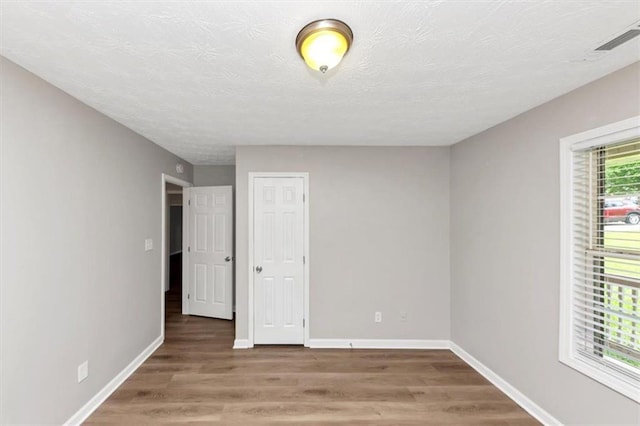 5514 E Stoneway Ct, Villa Rica, GA 30180 - unfurnished bedroom with wood finished floors, baseboards, a textured ceiling, and a closet