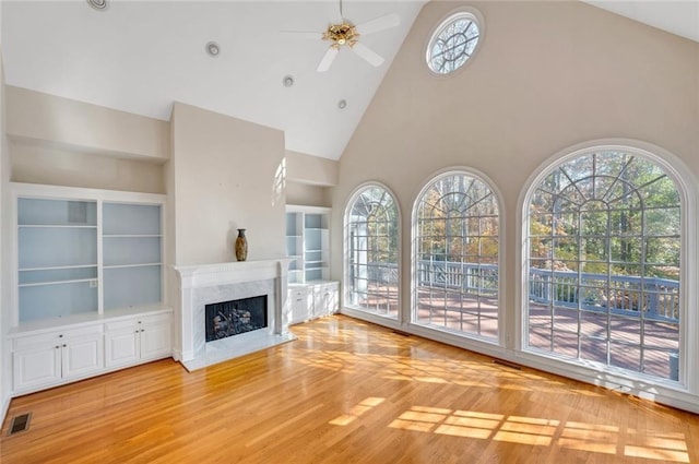 unfurnished living room with a high end fireplace, a wealth of natural light, hardwood / wood-style floors, and high vaulted ceiling