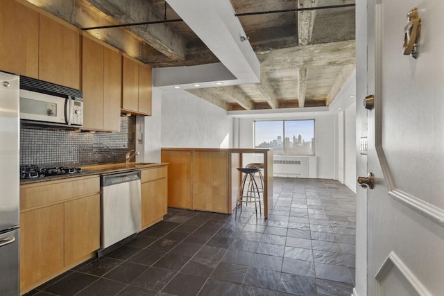 kitchen featuring a kitchen breakfast bar, dishwasher, gas stovetop, radiator heating unit, and backsplash