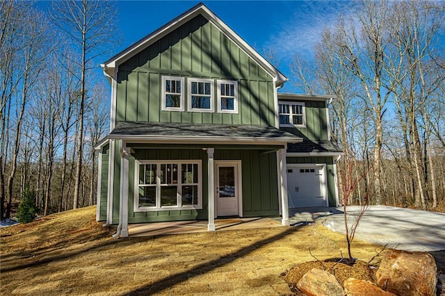 view of front facade with driveway, a shingled roof, an attached garage, covered porch, and board and batten siding