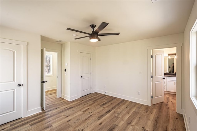 unfurnished bedroom with light wood finished floors, baseboards, and ensuite bathroom