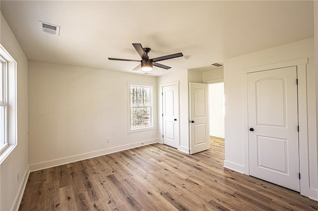 unfurnished bedroom featuring visible vents, baseboards, and wood finished floors