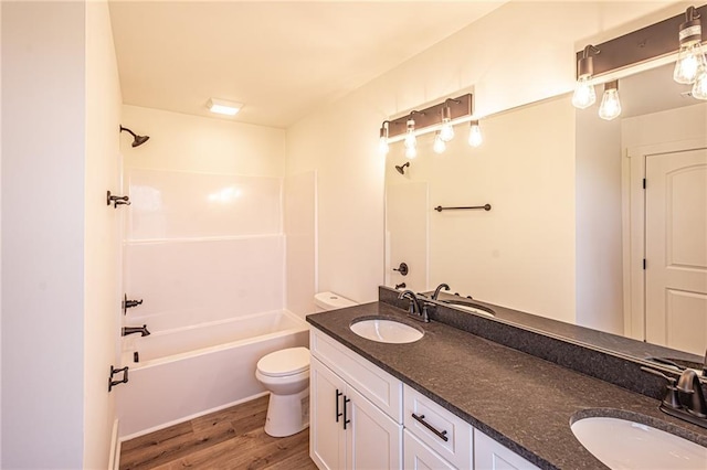 full bath featuring toilet, washtub / shower combination, a sink, and wood finished floors