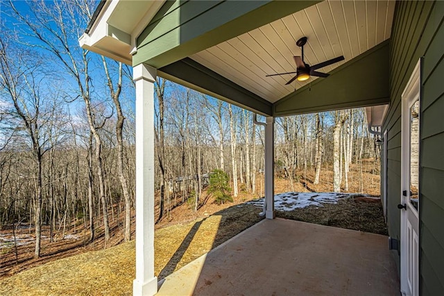 view of patio featuring ceiling fan and a wooded view