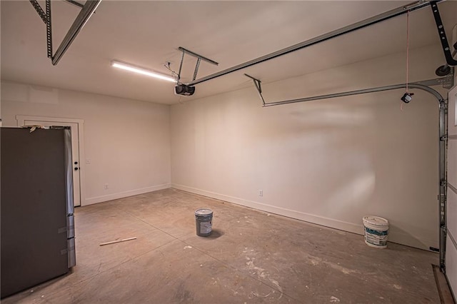 garage with baseboards, a garage door opener, and freestanding refrigerator