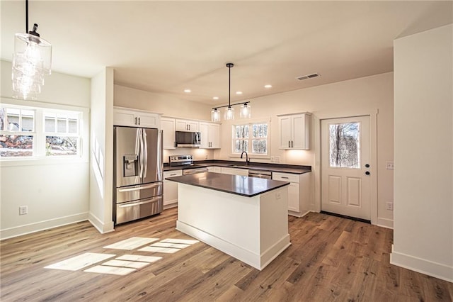 kitchen featuring dark countertops, visible vents, light wood-style flooring, appliances with stainless steel finishes, and white cabinets