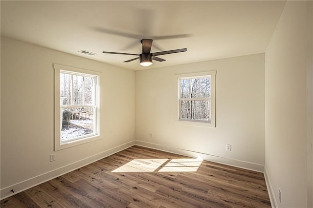 unfurnished room with visible vents, plenty of natural light, and wood finished floors