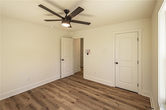 unfurnished bedroom with ceiling fan, wood finished floors, and baseboards