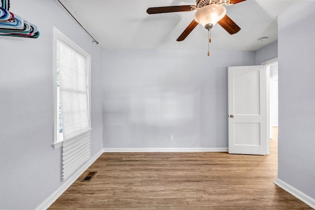 empty room featuring a healthy amount of sunlight, ceiling fan, and light wood-type flooring