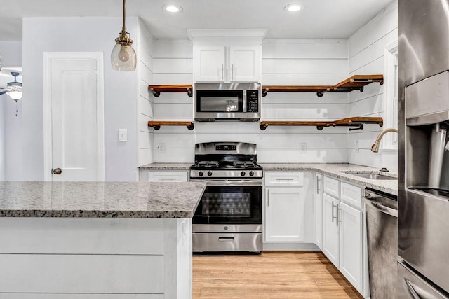 kitchen with white cabinetry, appliances with stainless steel finishes, light stone countertops, and sink