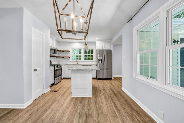 kitchen with appliances with stainless steel finishes, decorative light fixtures, a center island, and white cabinets