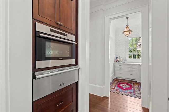 6440 Westchester Pl, Cumming, GA 30040 - kitchen with stainless steel oven, a warming drawer, dark wood-type flooring, light countertops, and pendant lighting