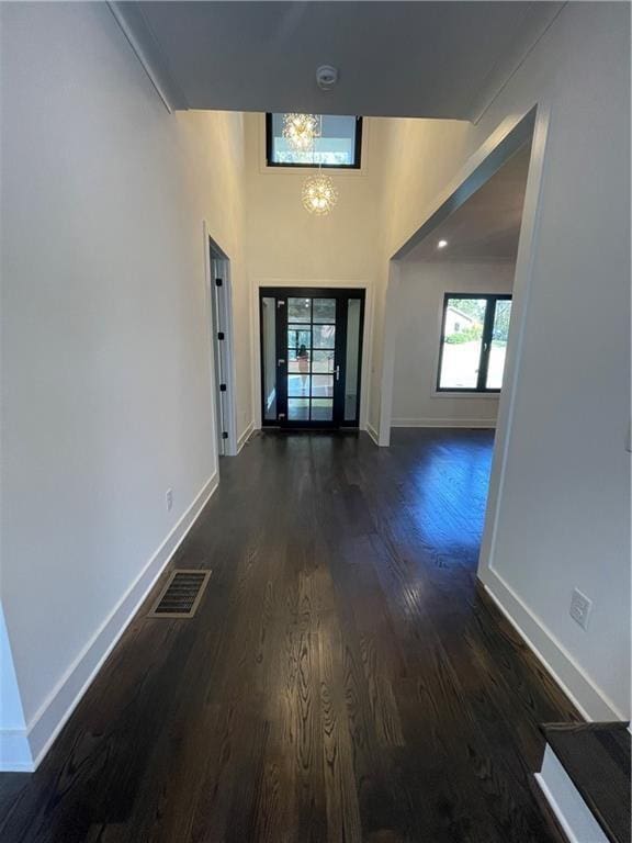 hall with dark wood-type flooring and a chandelier